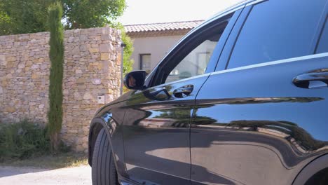 fllow shot of a male arriving in a black car to a house during sunset