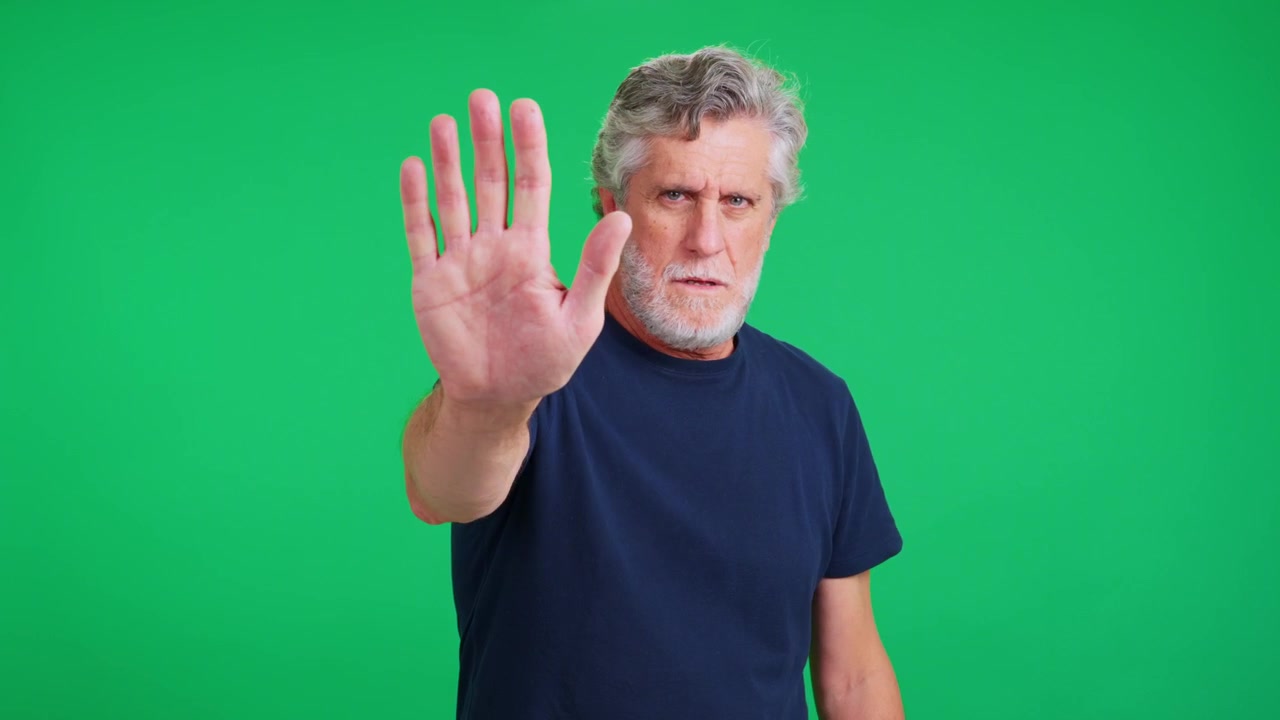 Serious Mature Man Making a Stop Gesture Against Green Screen
