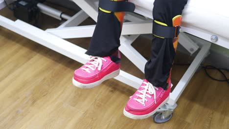 niño en fisioterapia con aparatos ortopédicos para las piernas