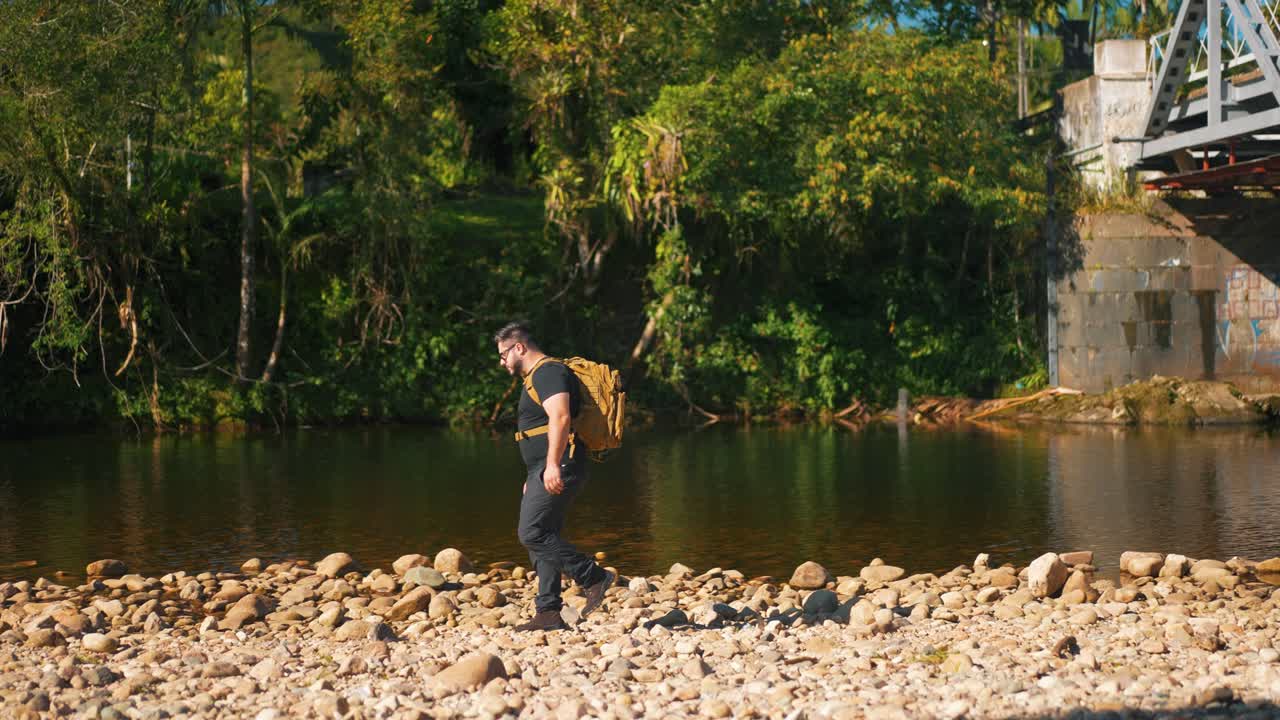 joven excursionista masculino en caminatas a lo largo de un río rocoso día caluroso de verano, actividad al aire libre y viajes en la naturaleza