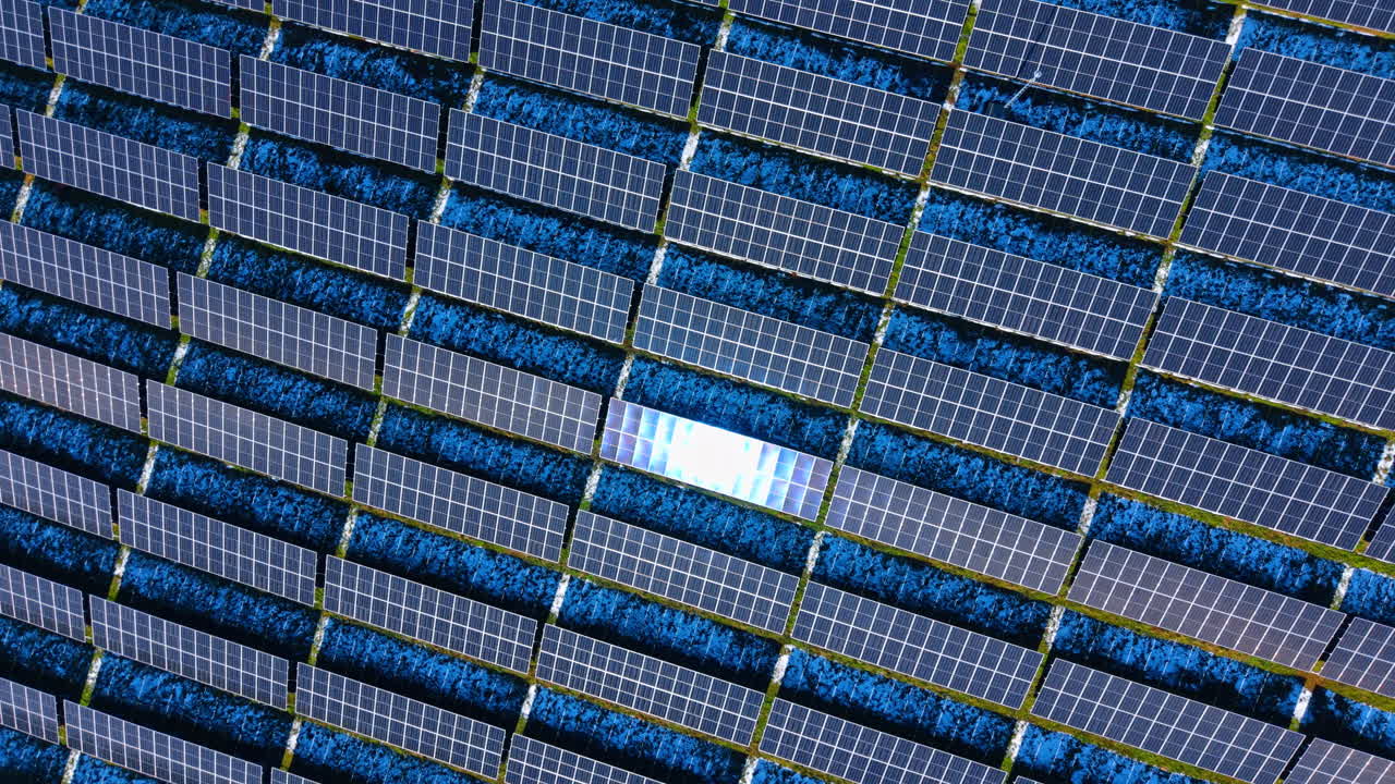 Motivo astratto di pannelli solari con riflesso del sole. Vista geometrica dall'alto di file di pannelli solari con un pannello che riflette la luce solare intensa durante la stagione invernale.