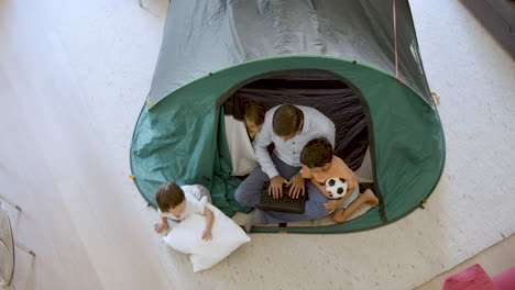 dad and three kids playing camping in living room