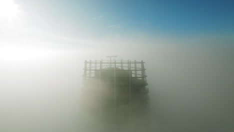 video aéreo: un dron estacionario captura nubes dinámicas de la mañana, revelando brevemente un rascacielos solitario a la izquierda