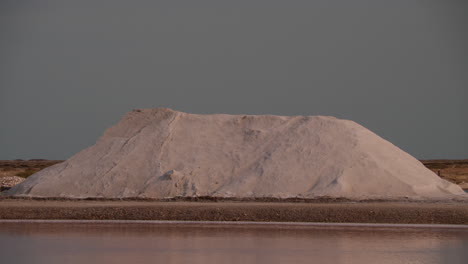 large pile of salt by a pink lake