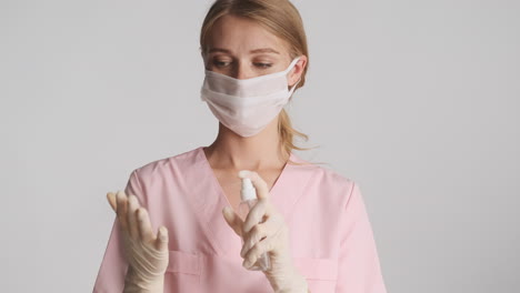 caucasian female doctor in medical gloves and mask using hand sanitizer.