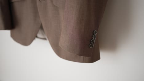 tailored brown suit sleeve with four buttons shown in a minimal fashion focused frame