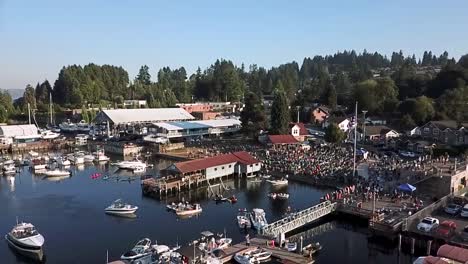 a crowd of people watching a concert at the skansie brothers park and netshed in gig harbor, washington on a sunny day - aerial drone