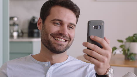 joven feliz teniendo video chat usando un teléfono inteligente disfrutando de chatear en línea con un amigo relajándose en casa