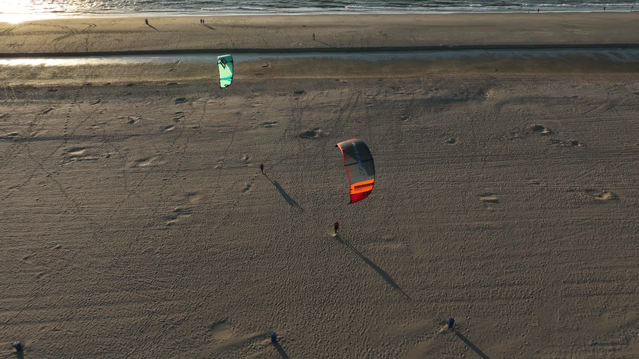 toma aérea de drones de kitesurfistas después de su sesión caminando en la playa con sus cometas en el aire