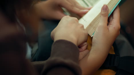 Detailed-closeup-of-friends-crossing-hands-leaning-on-each-other-to-read-book