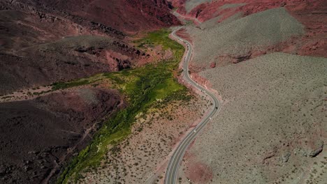 Drone-shot-following-a-car-driving-through-the-Quebrada-las-Angosturas-in-Catamarca,-Argentina