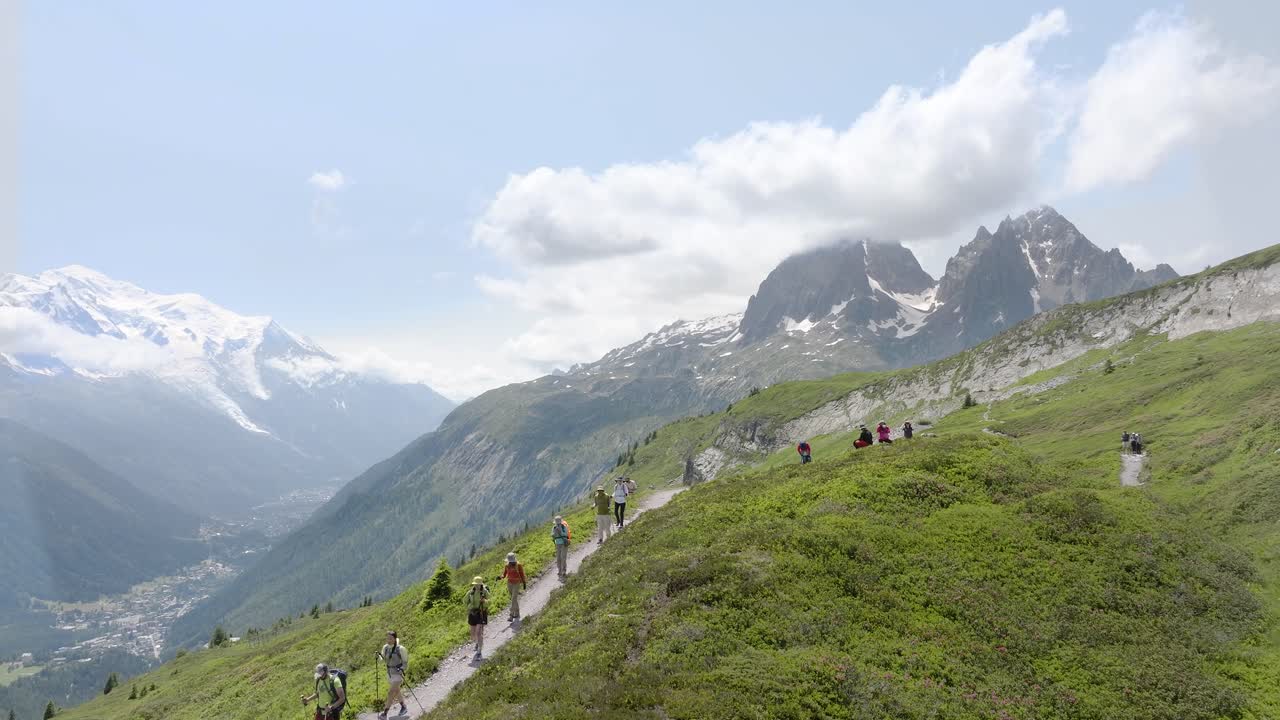 Hikers crossing the alpine meadows on the Tour du Mont Blanc, with stunning mountain views in the background.