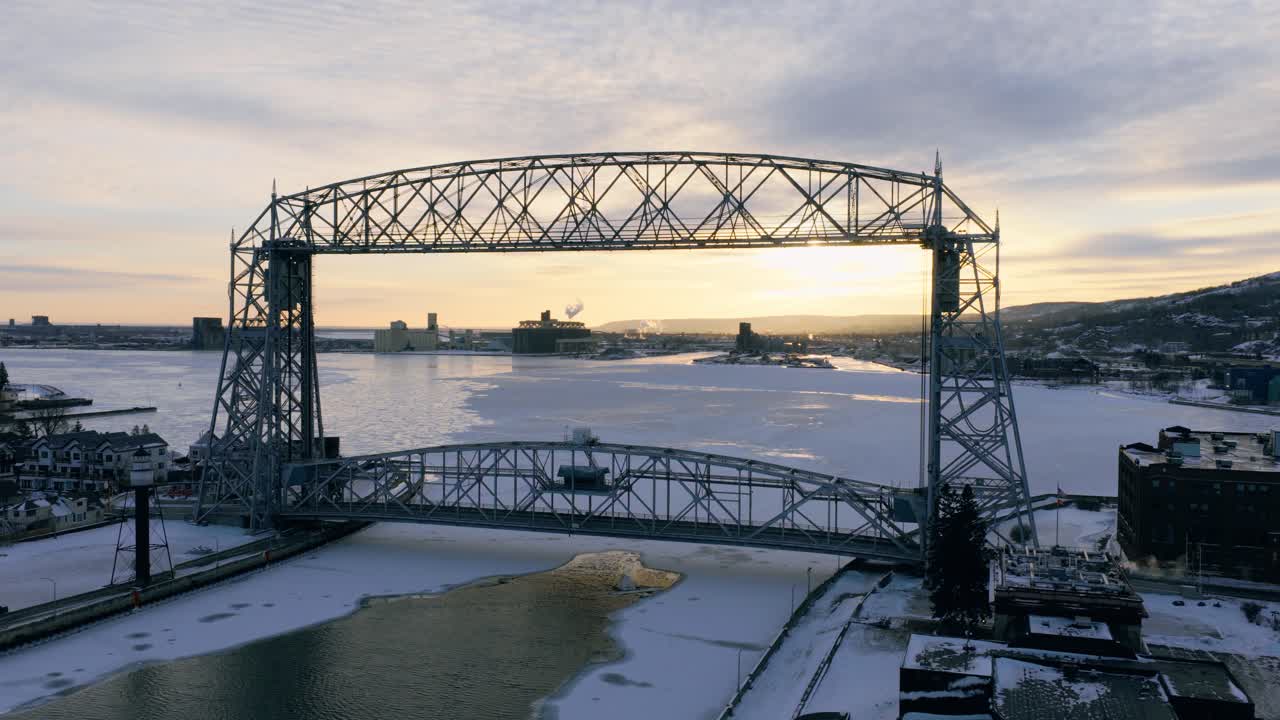 Maestosa veduta aerea del Duluth Aerial Lift Bridge su un porto ghiacciato durante un vibrante tramonto invernale, che mette in mostra l'iconica architettura industriale
