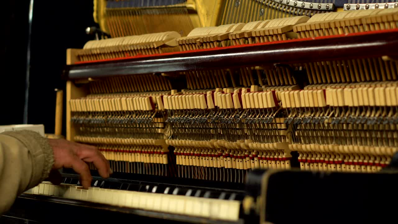 anciano en el metro subterráneo tocando el piano con el mecanismo abierto og cuerdas y martillos