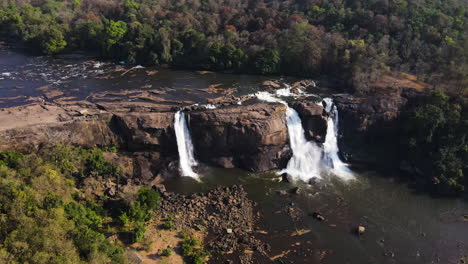 waterfalls flowing down rocky cliff in india - aerial drone shot