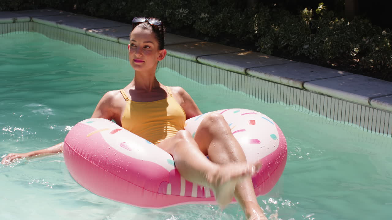 Woman relaxing on pink pool float, enjoying sunny day at swimming pool