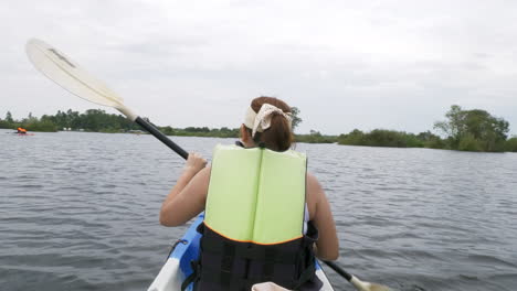 feliz joven asiática haciendo kayak en un bosque de manglares en vacaciones de verano remando en un bote de canoa en un lago forestal