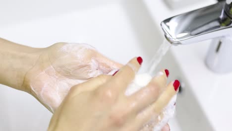 close-up of hands washing with soap and water in a sink
