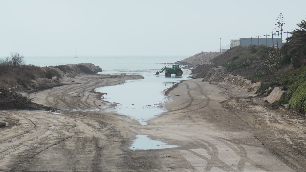 il trattore sposta la sabbia vicino al mare, durante la giornata nuvolosa