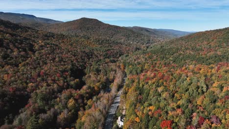 road through forested mountains in autumn - aerial drone shot