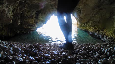 vista dentro de la caverna en kefalonia, grecia con un turista masculino caminando hacia el mar