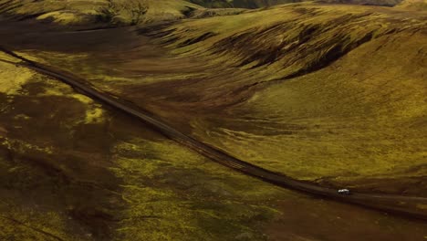 aerial view over a four wheel drive car traveling on a dirt road through icelandic highlands