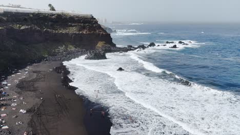 Rompiendo-Olas-En-Una-Playa-De-Arena-Negra-En-Un-Día-Soleado