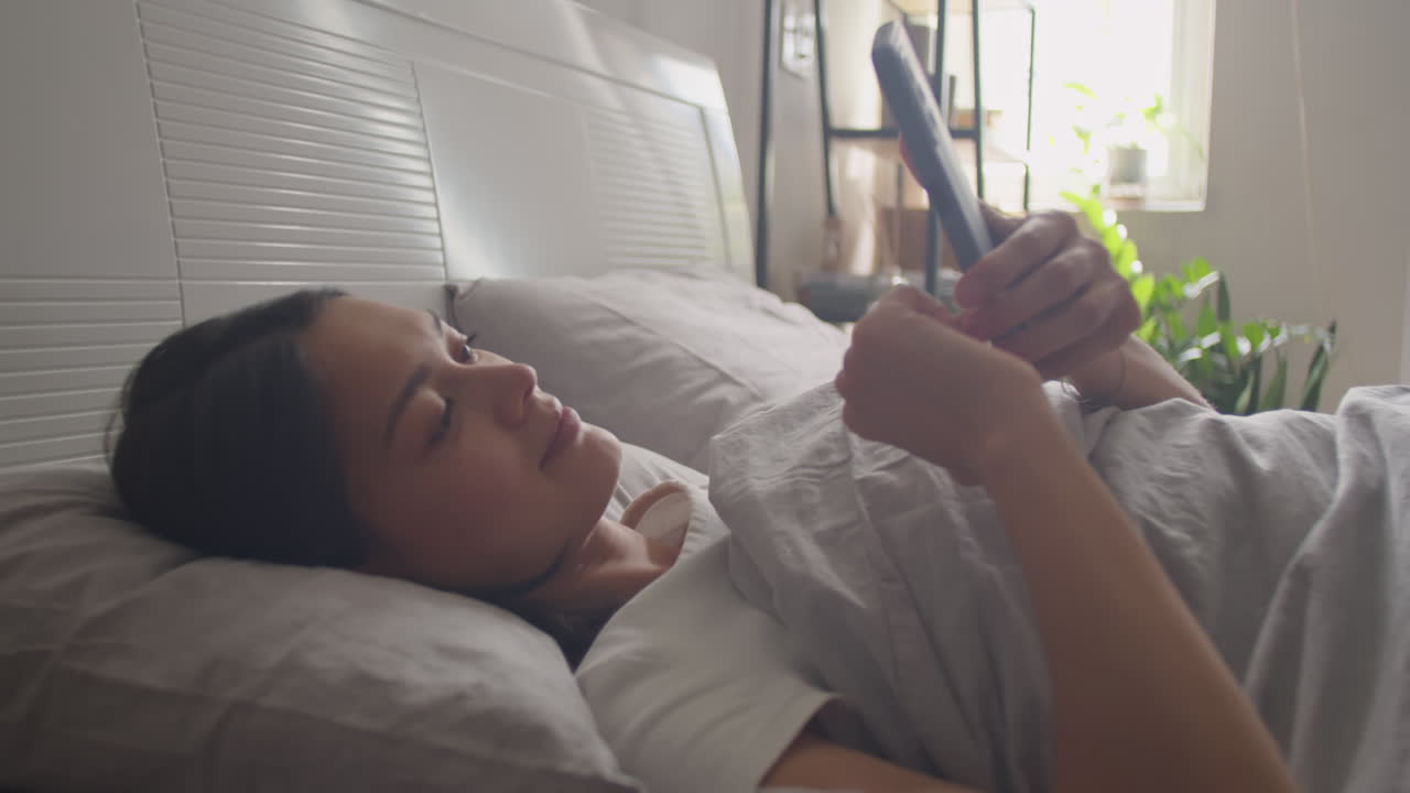 Woman Waking Up in Bed and Taking Phone