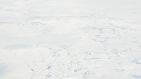 toma en cámara lenta de vista aérea desde un avión sobre témpanos de hielo en el océano - inclinada hacia las nubes y el cielo azul