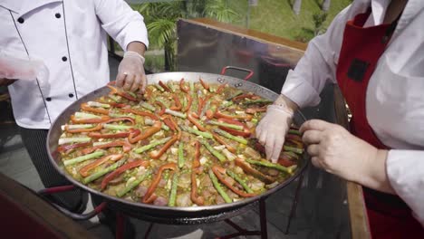 dos chefs, hombres y mujeres, preparando una paella de estilo español en costa verde, lima, perú