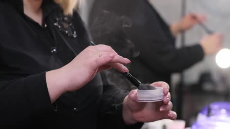 make-up master puts powder on a pussy brush