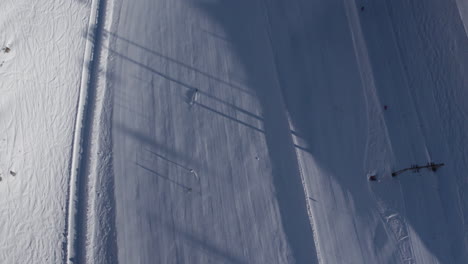 Aerial-top-down-shot-of-skier-skiing-over-snowy-slope-in-Austrian-alps-during-sunlight