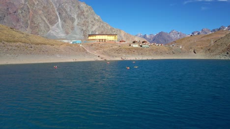 Aerial-view-dolly-in-of-kayaks-in-the-Laguna-del-Inca,-Portillo-hotel-among-the-Chilean-Andes-mountains,-sunny-day