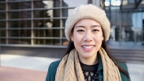 asian woman looking at camera while posing outside office building.