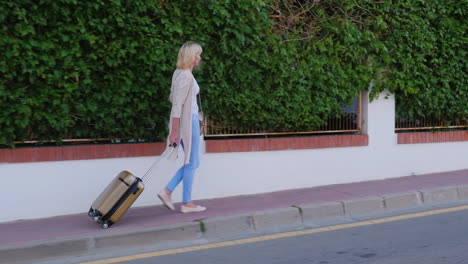 Woman-With-Travel-Bag-On-Wheels-Comes-To-The-Door-Of-The-Hotel-Arrival-At-The-Hotel-Or-On-Vacation-S