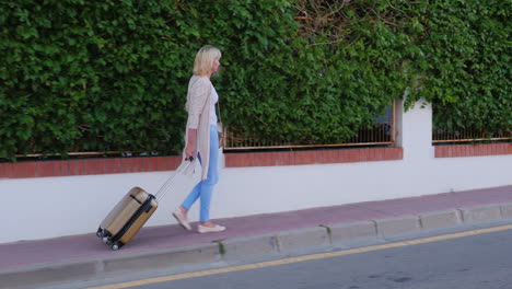 woman with travel bag on wheels comes to the door of the hotel arrival at the hotel or on vacation s