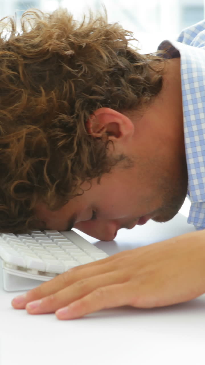 지친 사업가가 키보드 위에 머리를 고 잠을 자고 있습니다.