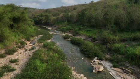 Drone-Pasando-A-Lo-Largo-De-Secciones-Del-Río-Oyo-Cerca-Del-Puente-Gantung-Wanagama-Al-Comienzo-De-La-Estación-Seca---Con-Follaje-A-Juego