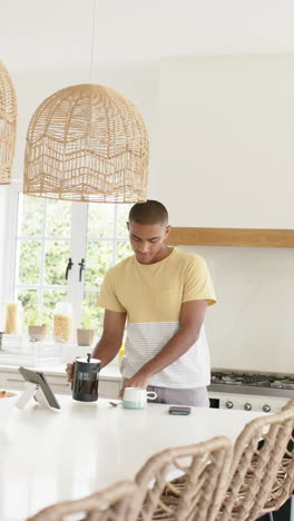 vertical video of anglo indian man making coffee in bright kitchen, slow motion