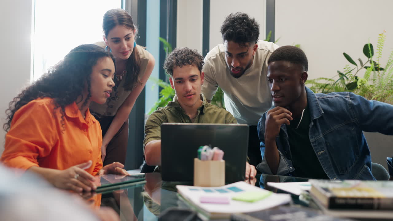 Diverse Group of Young Professionals Collaborating on Laptop in Modern Office