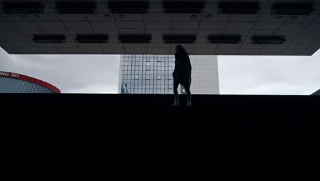 silhouette girl walking stairs in dark underground station metro in city.