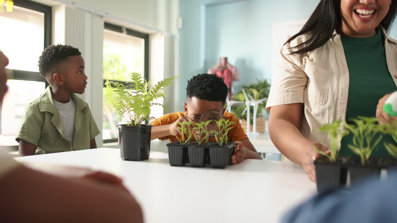 African American teacher guiding boy picking magnifier and studying seedling tray in class for STEM
