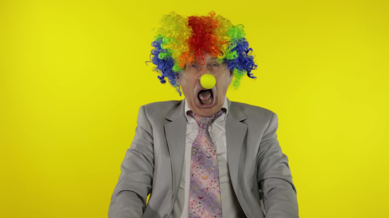 el jefe del empresario payaso senior haciendo caras tontas. fondo amarillo
