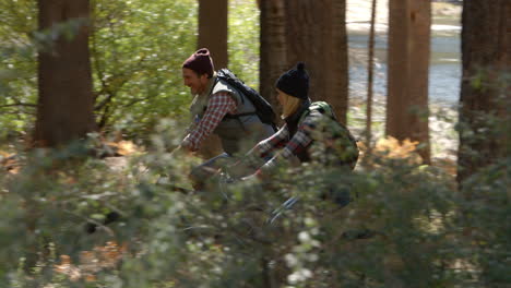 pareja hablando mientras montan bicicletas de montaña en el bosque, pan apretado