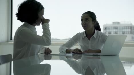 Smiling-businesswomen-using-laptop-and-talking