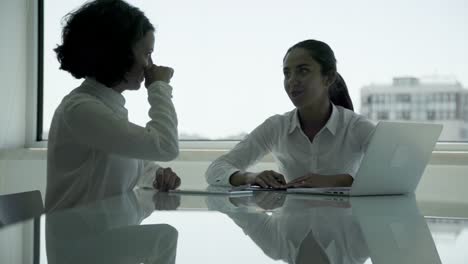 smiling businesswomen using laptop and talking