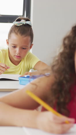 video of focused diverse girls sitting at school desks and learning