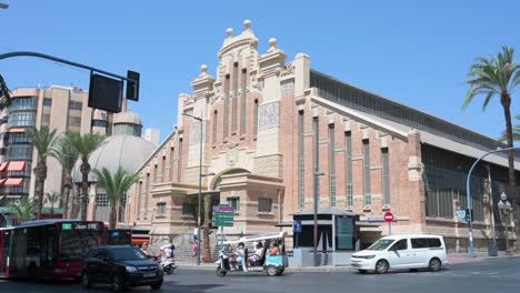 a broad view of the historic alicante central market, a two-floor structure from 1922, featuring a variety of stalls with fresh seafood, meats, produce, pastries, and tapas.