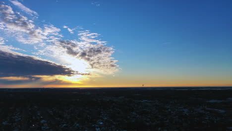 a golden sunrise with blue skies with some clouds around the sun