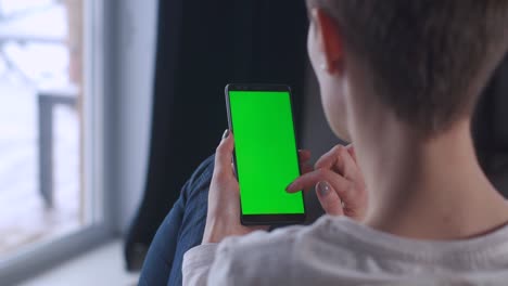 primer plano de una mujer con la mano sosteniendo una pantalla verde modelo de teléfono inteligente. teléfono móvil de niña. dedos pantalla moderna teléfono celular tocando mensaje de desplazamiento. clave de croma pantalla verde nuevo concepto de tecnología.